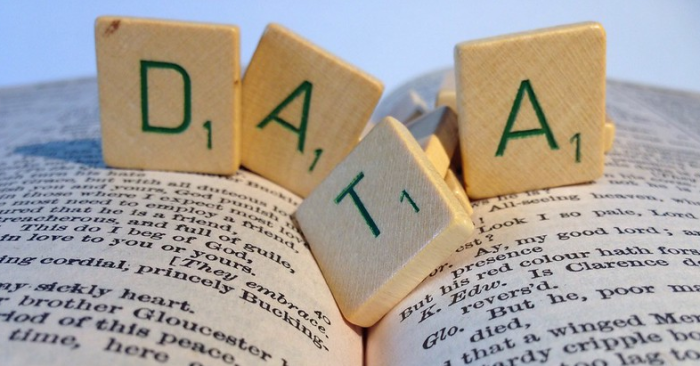 Bilde av åpen bok med spillbrikker oppå som staver "data"